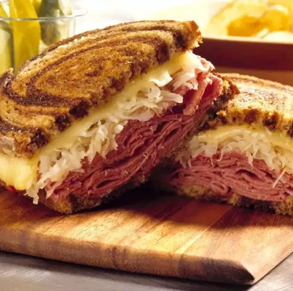 A sandwich cut in half on a wooden cutting board.