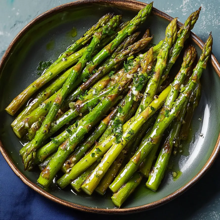 Bright green asparagus spears on a plate with butter and seasoning.