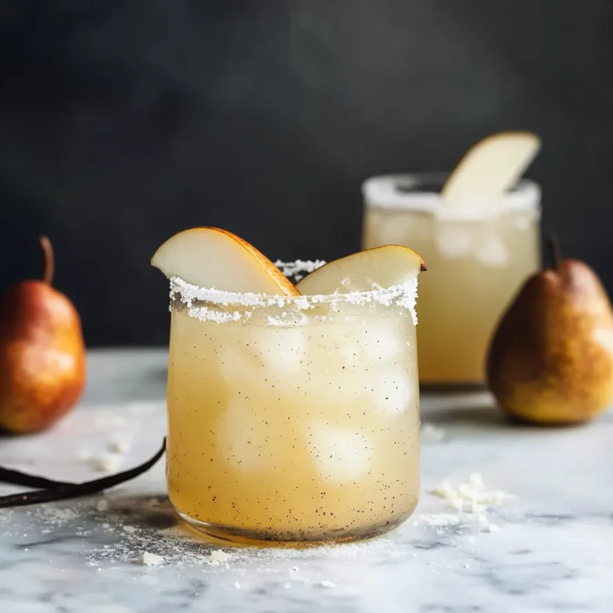 A glass of tequila with a slice of pear on top.