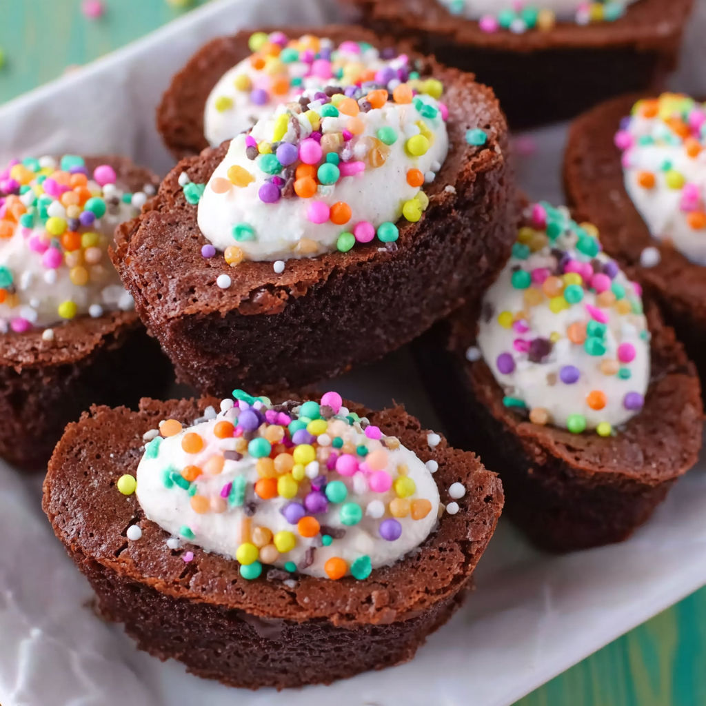 A plate of brownies with white frosting and sprinkles.