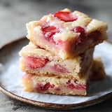 A plate stacked with strawberry and lemon dessert bars.