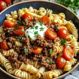 A delicious pasta bowl topped with meat and tomatoes.