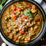 A bowl of soup with tomatoes and beans.