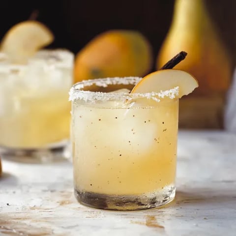 A glass of alcohol with a slice of lemon in it.