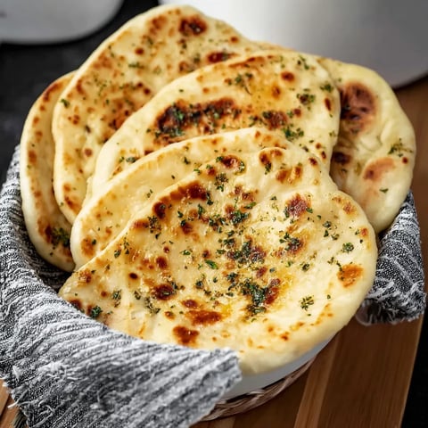 A basket of bread with green herbs on top.