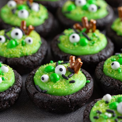 A plate of green and black cookies with eyes.