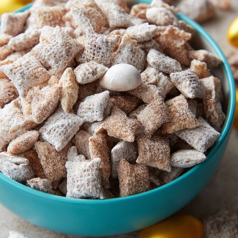 A bowl of puppy chow with a white marshmallow in the middle.
